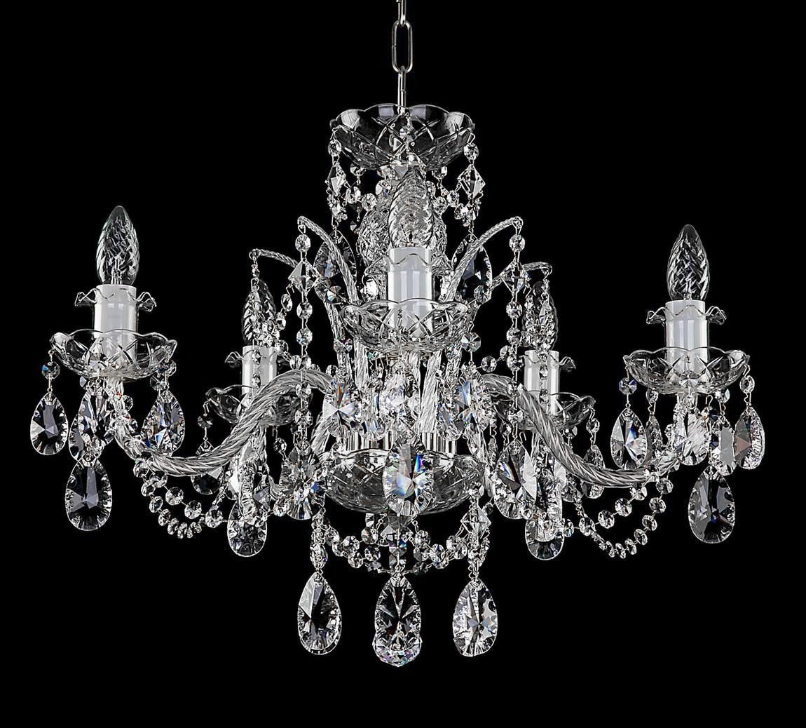 Second plan du lustre, bras et pendants de cristal taillé sur fond noir.