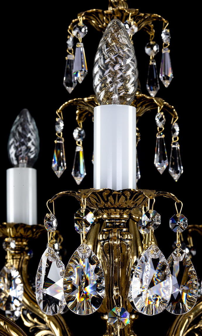 Vue rapprochée du fleuron en cristal et de la colonne dorée du luminaire