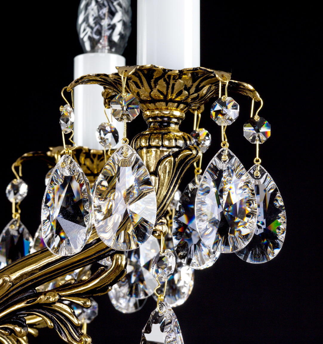 Gros plan sur les pendeloques de cristal en goutte suspendues à une coupelle dorée ciselée