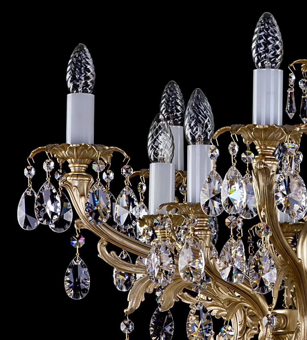 Gros plan sur les bras dorés, bougies blanches et pendentifs en cristal facetté suspendus.