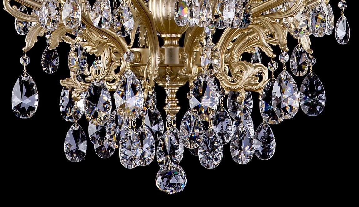 Détail du centre du lustre avec grappes de cristaux en goutte et volutes dorées finement ciselées.