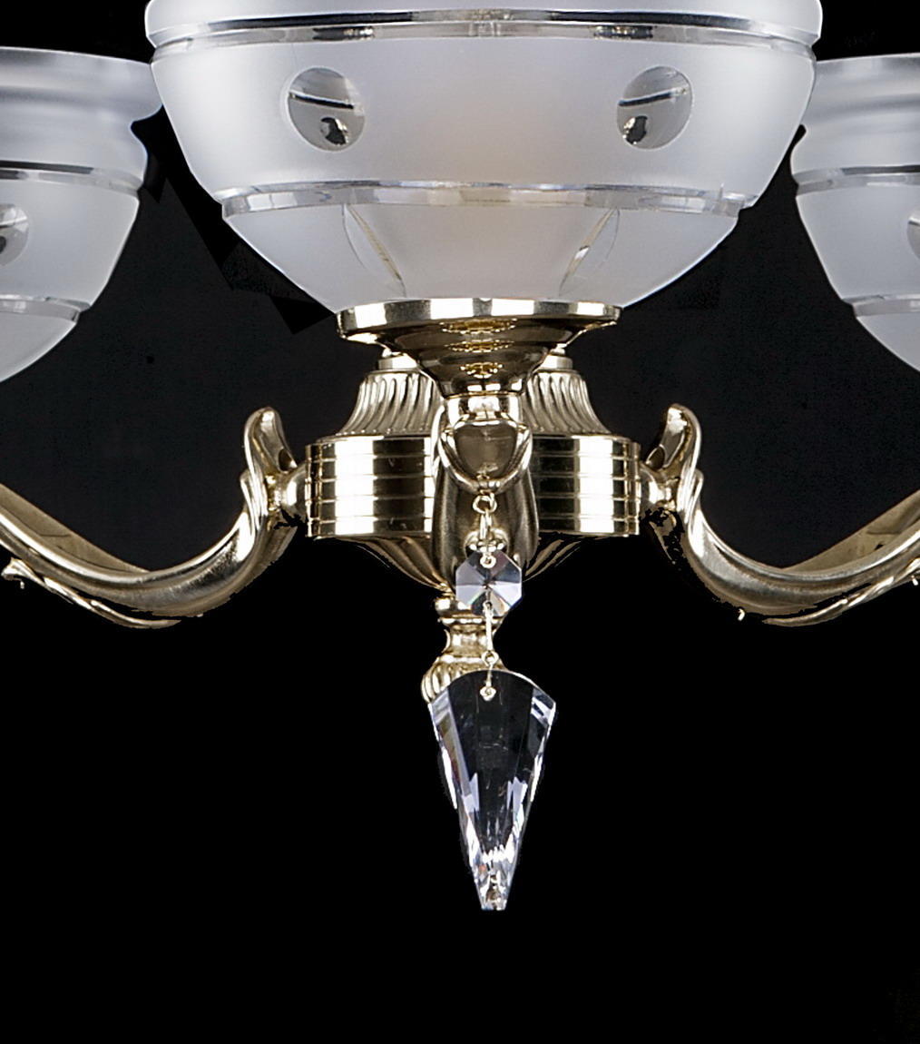 Détail du centre doré du lustre avec trois bras recourbés et pampille de cristal.