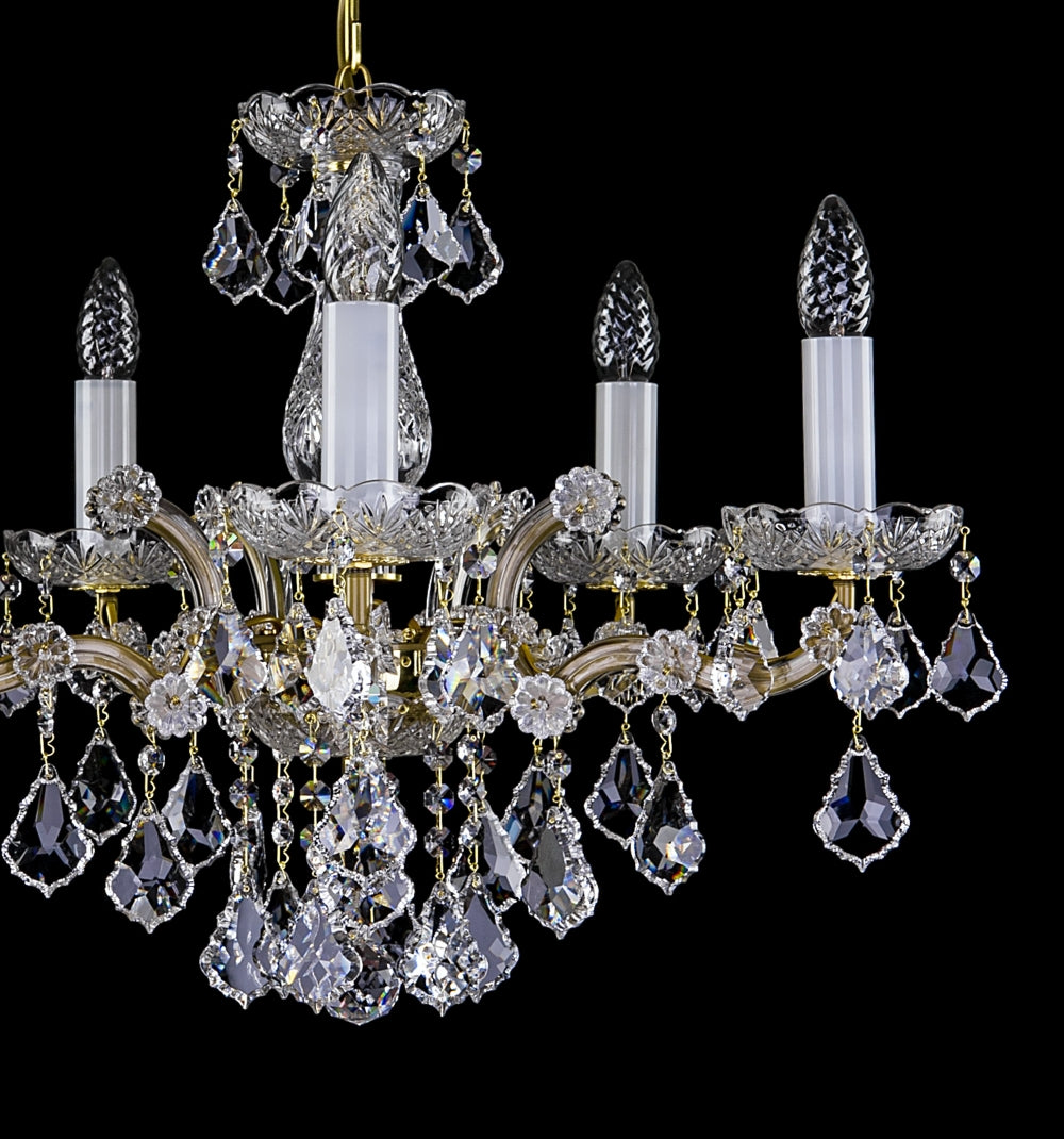 Lustre de face montrant les cinq bras dorés, bougies et gouttes de cristal facettées.