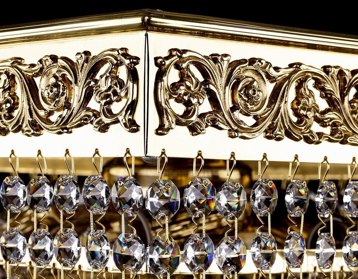 Détail de la frise dorée ciselée et des pendeloques rondes en cristal taillé