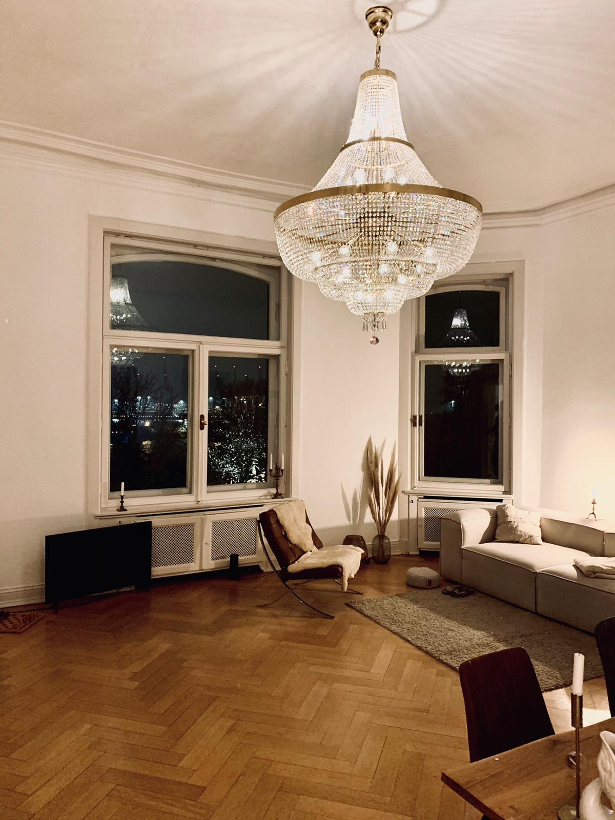 Mise en ambiance dans un séjour, lustre allumé au-dessus des fauteuils.