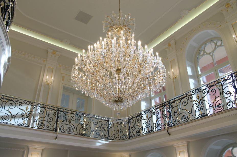 Vue d'ensemble depuis la mezzanine, le lustre éclairé domine un grand hall blanc.