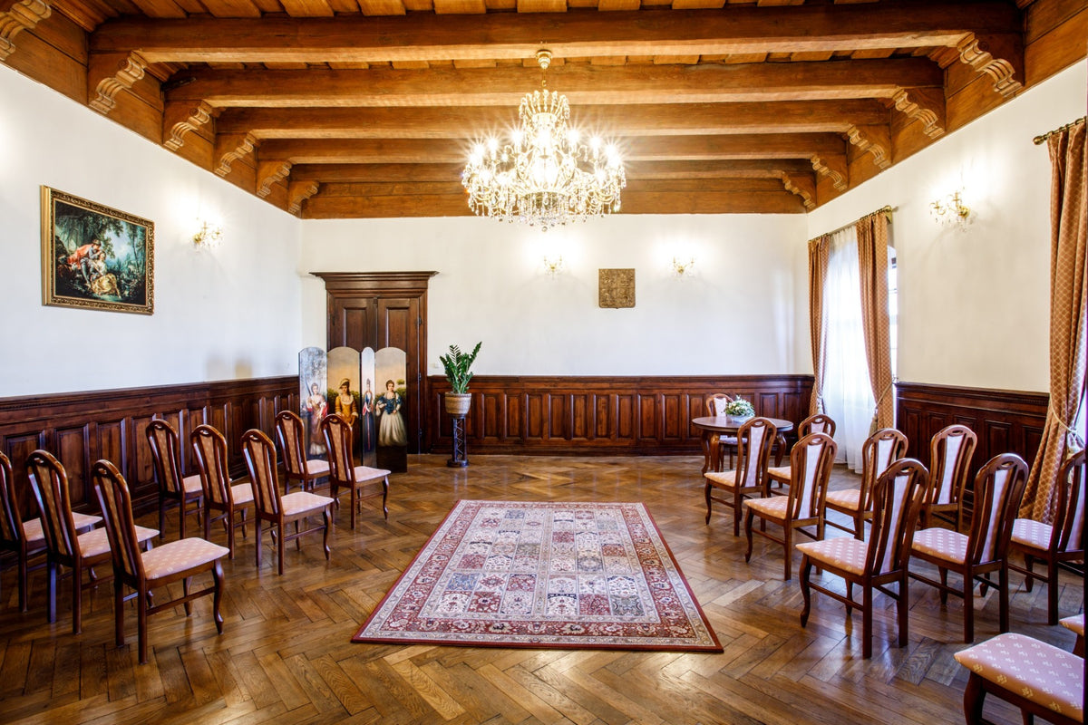 Vue large de la salle : lustre suspendu au centre, mobilier et parquet