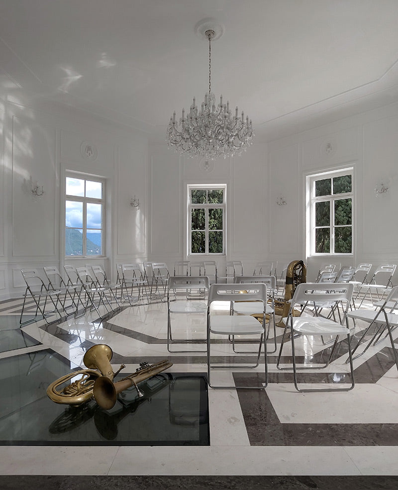 Lustre en cristal éclairant une salle blanche aux chaises alignées
