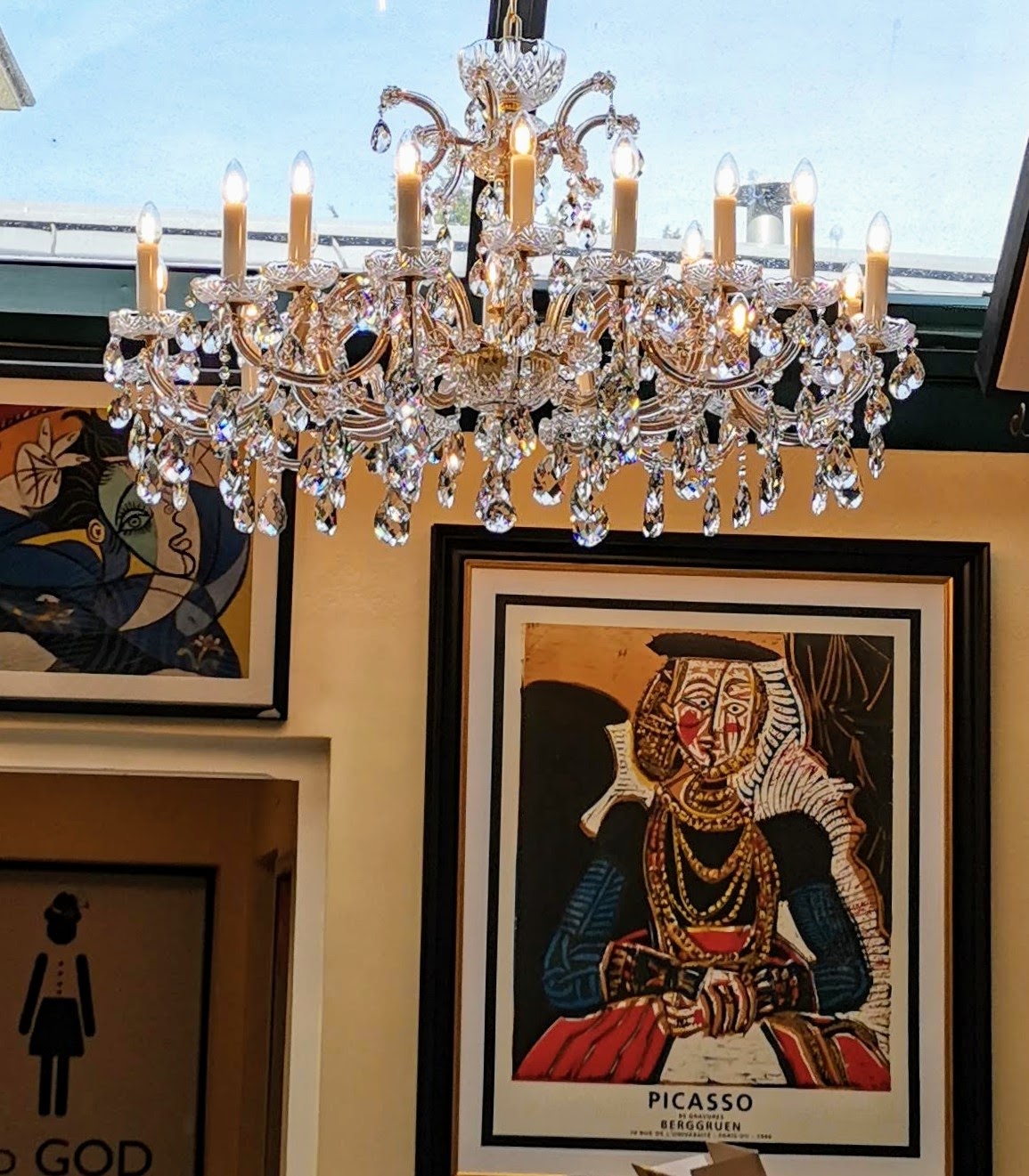 Lustre suspendu dans un intérieur, devant des tableaux encadrés et une verrière