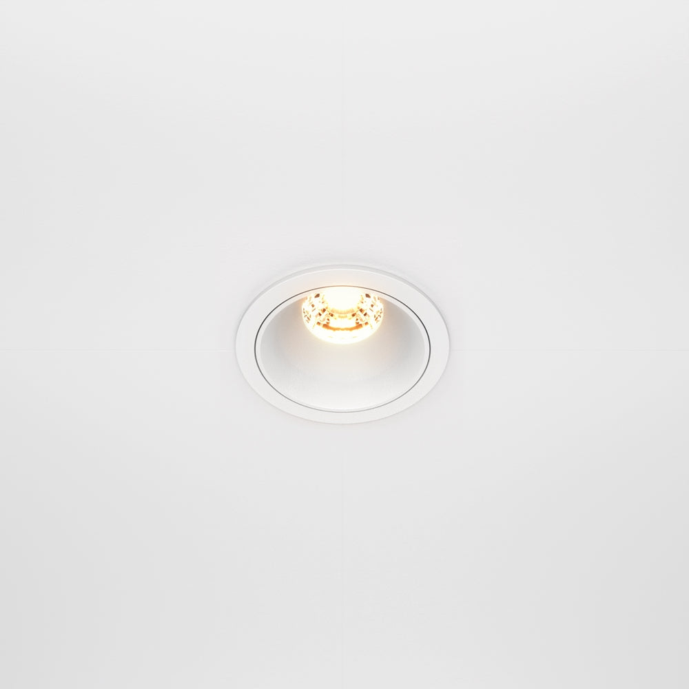 Vue de face d'un spot encastré rond blanc allumé sur un plafond