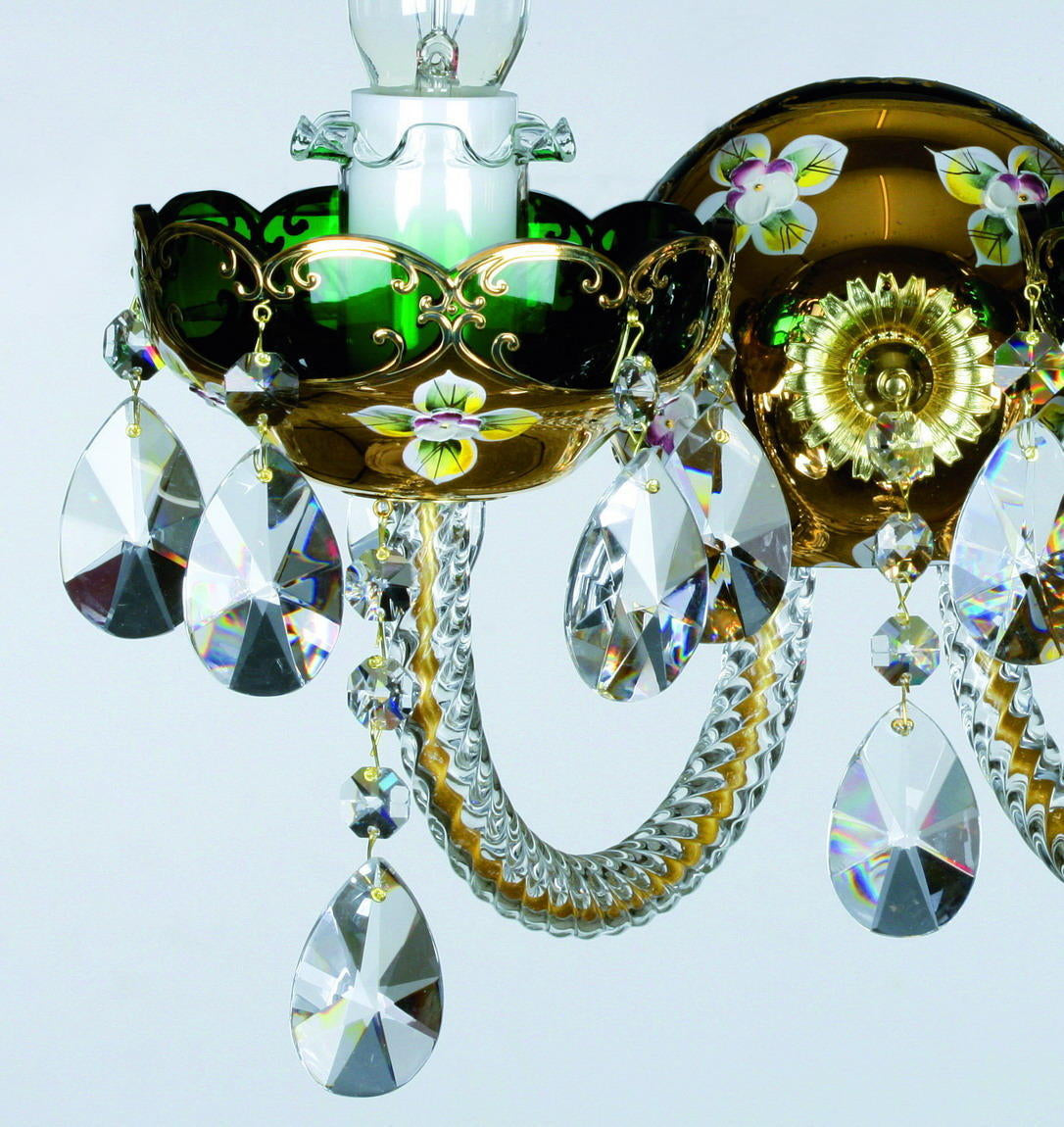 Gros plan sur la coupe en verre vert ciselé et les pendants de cristal facetté.