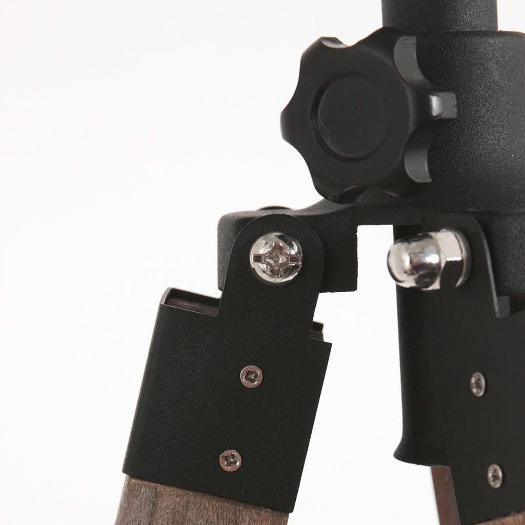 Vue rapprochée du raccord métallique noir reliant les trois pieds en bois.