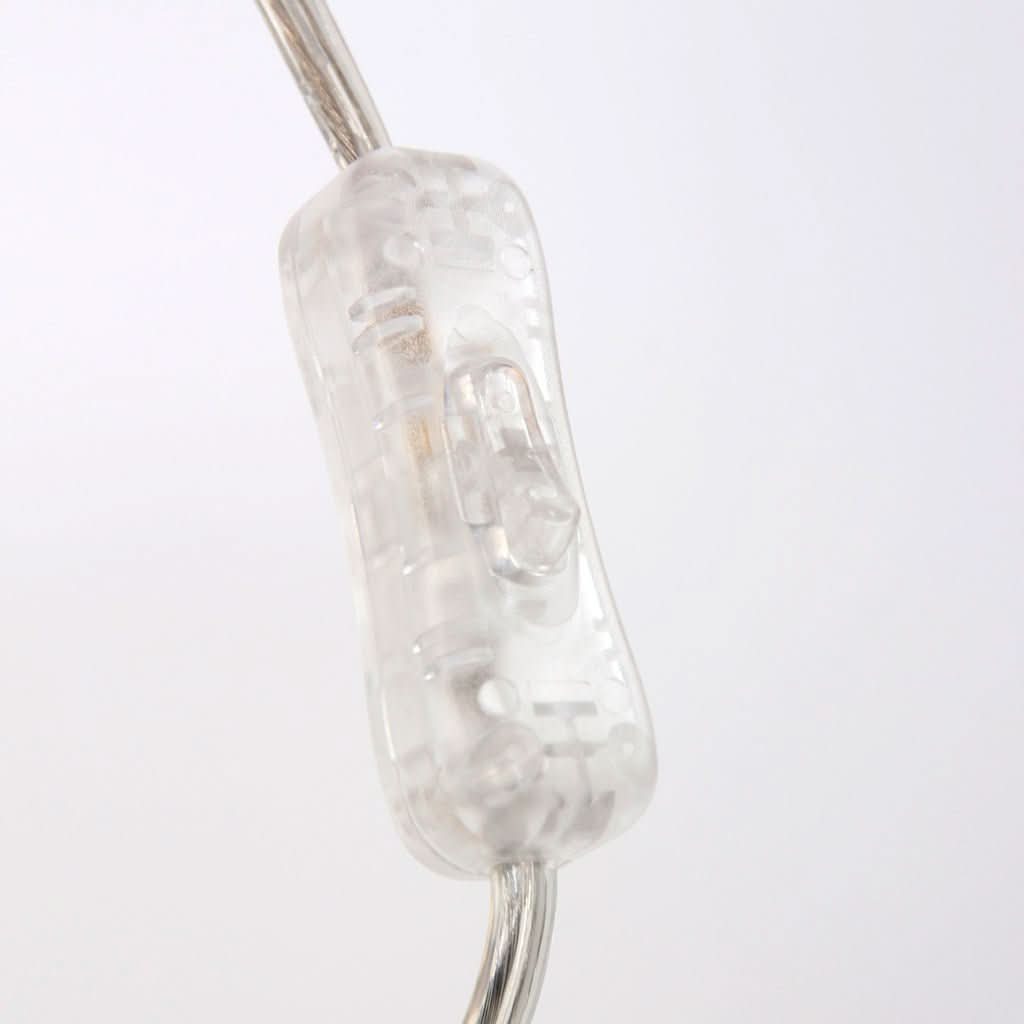 Gros plan sur l'interrupteur transparent intégré au câble électrique de la lampe.