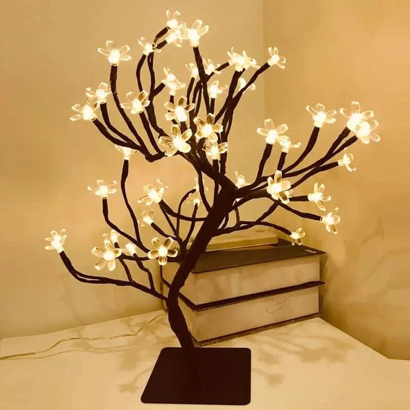 Lampe arbre à fleurs lumineuses posée sur un meuble, ambiance chaleureuse.