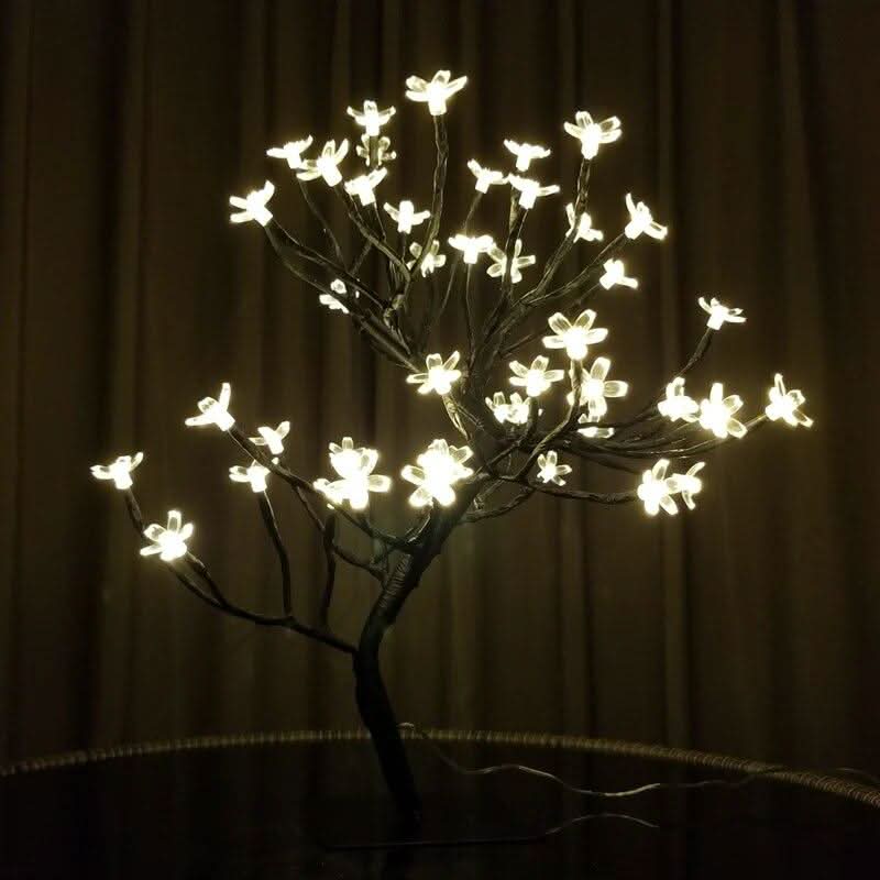 Vue de face sur fond sombre, branches noires et fleurs LED allumées.