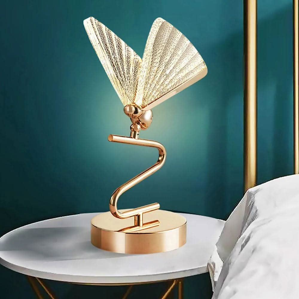 Lampe papillon dorée posée sur table blanche devant un mur bleu canard