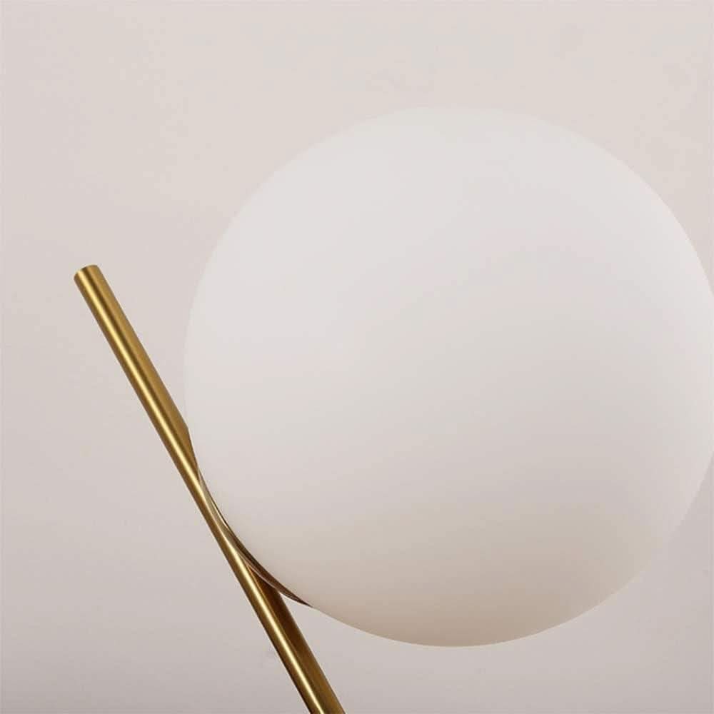 Gros plan sur la sphère de verre blanc et le bras métallique doré incliné.