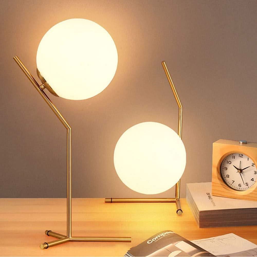 Deux lampes à sphère lumineuse sur un bureau en bois avec réveil et revues.