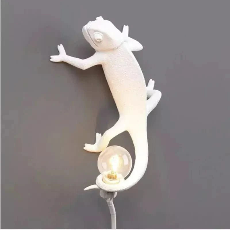 Caméléon blanc de profil fixé sur un mur gris, ampoule allumée.