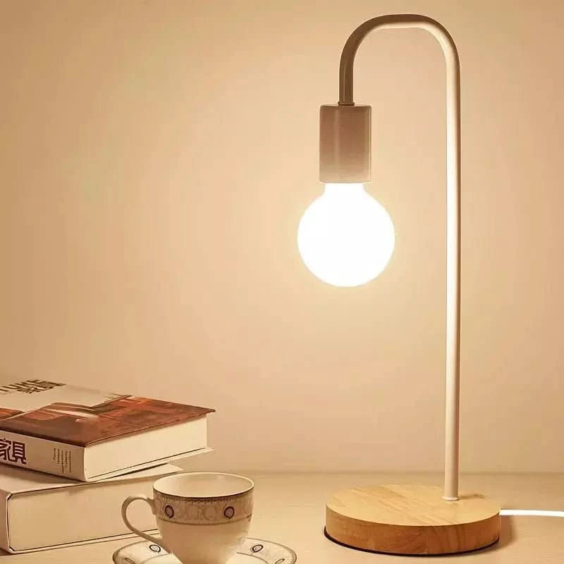 Lampe de bureau blanche sur socle en bois, allumée près de livres et d'une tasse