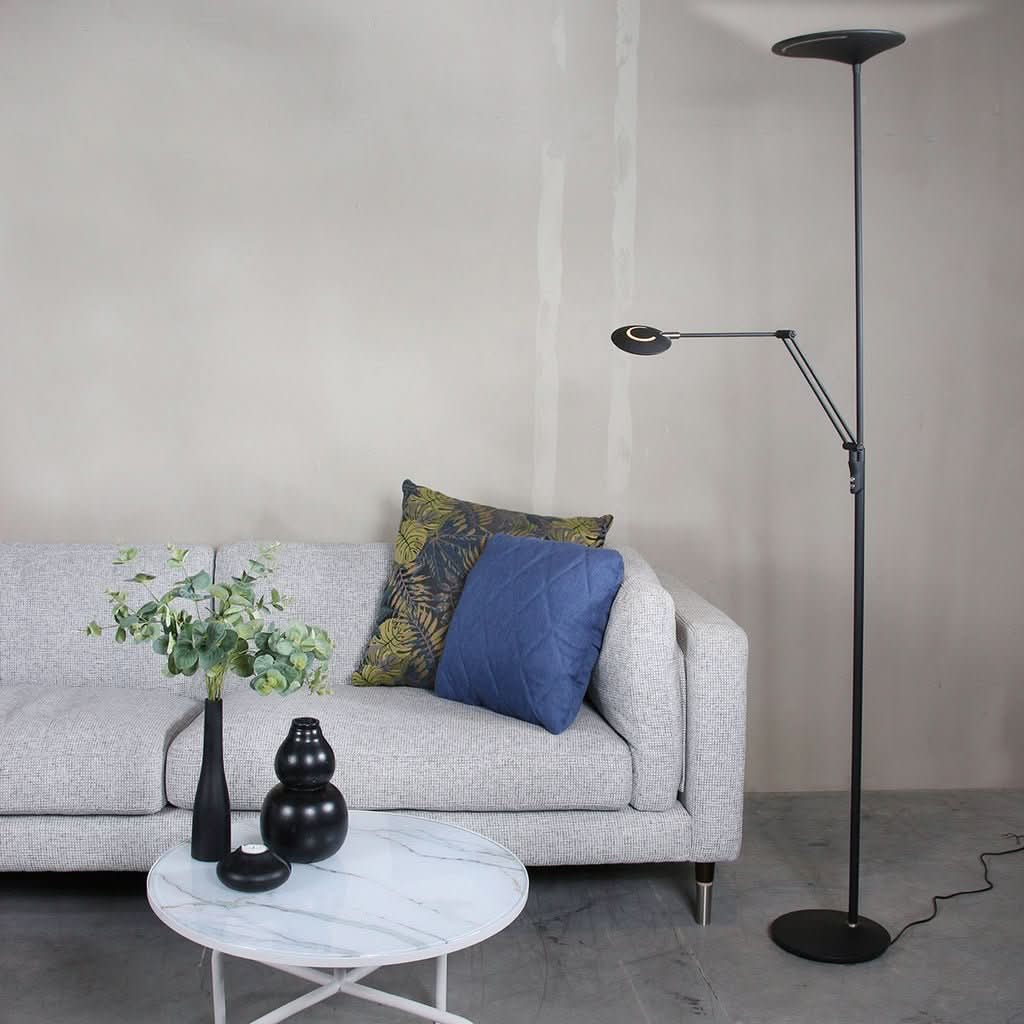 Lampe de sol noire devant un mur beige, canapé clair et table basse en marbre.