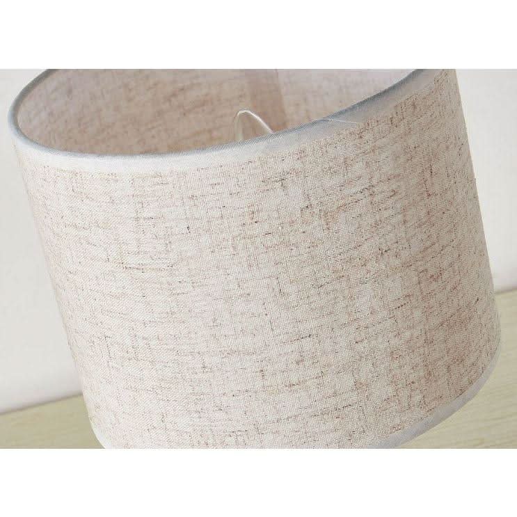 Gros plan sur la texture tissée de l'abat-jour beige et sa couture