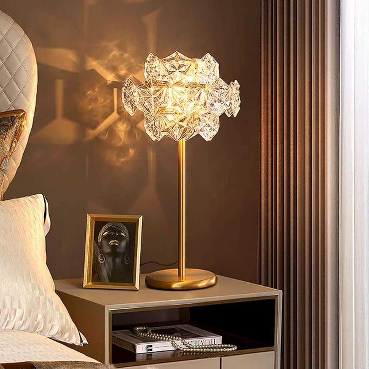 Lampe allumée sur chevet, lumière chaude projetant des motifs sur le mur.