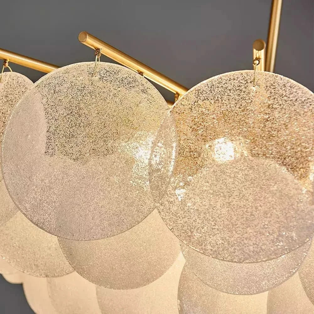 Détail des disques de verre granité translucide suspendus aux tiges dorées.