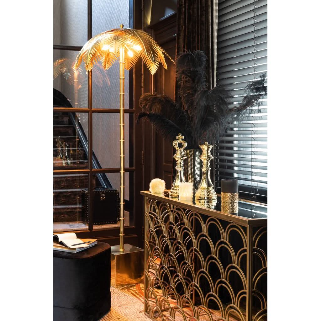 Lampe allumée dans un intérieur chic, près d'un meuble doré et de plumes noires.