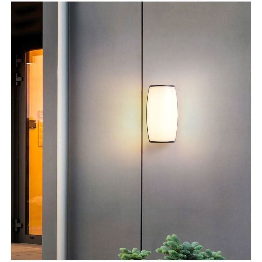 Applique ovale en verre opalin blanc fixée sur une façade grise, porte vitrée