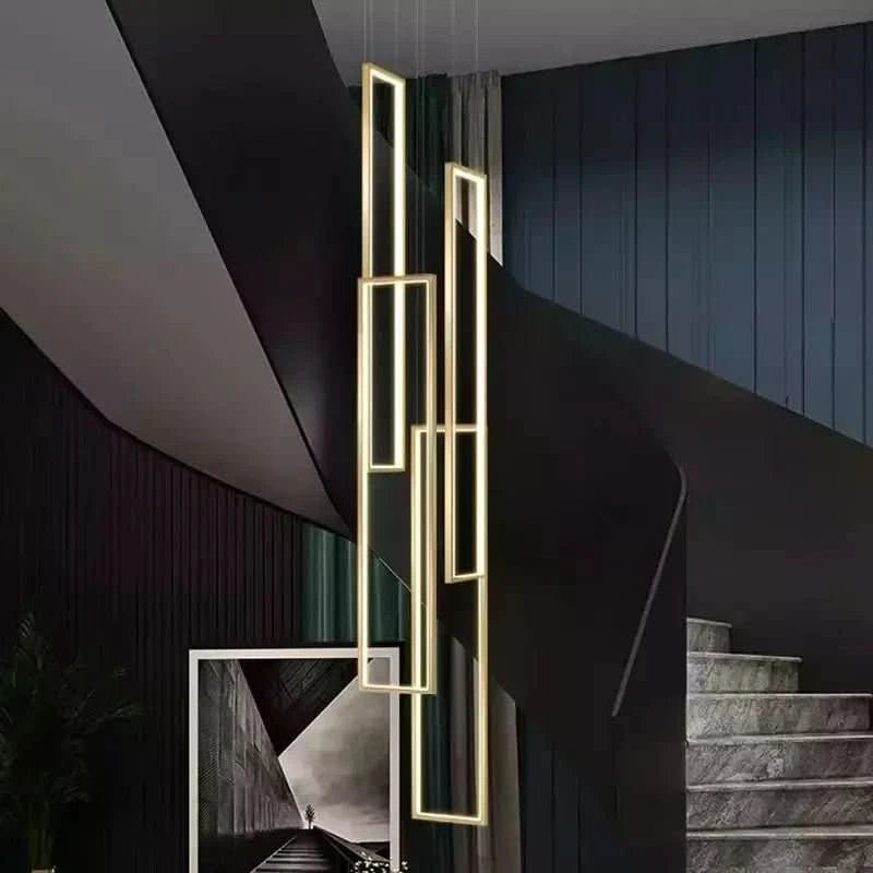 Grande suspension rectangulaire dorée devant un mur sombre et une photographie encadrée au sol.