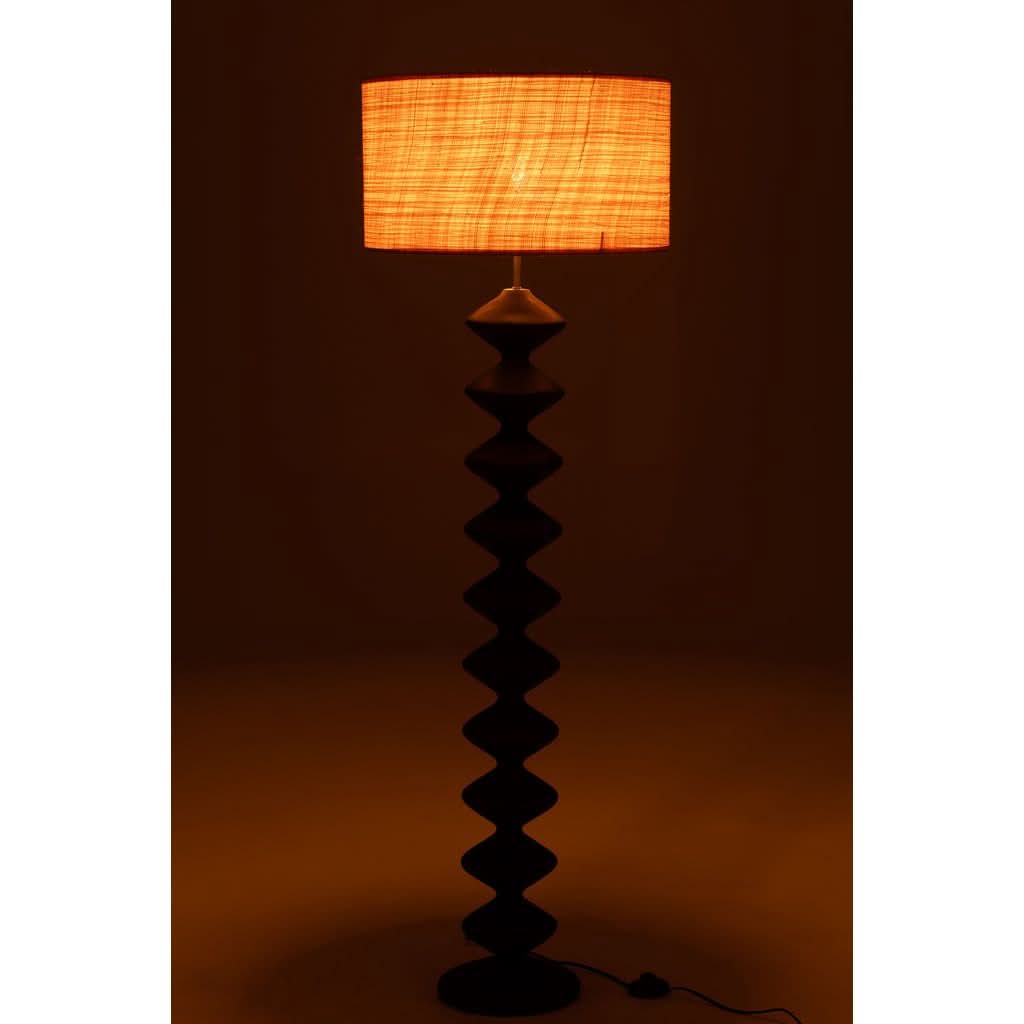 Lampe allumée dans ambiance sombre, abat-jour orange texturé et base noire découpée en silhouette