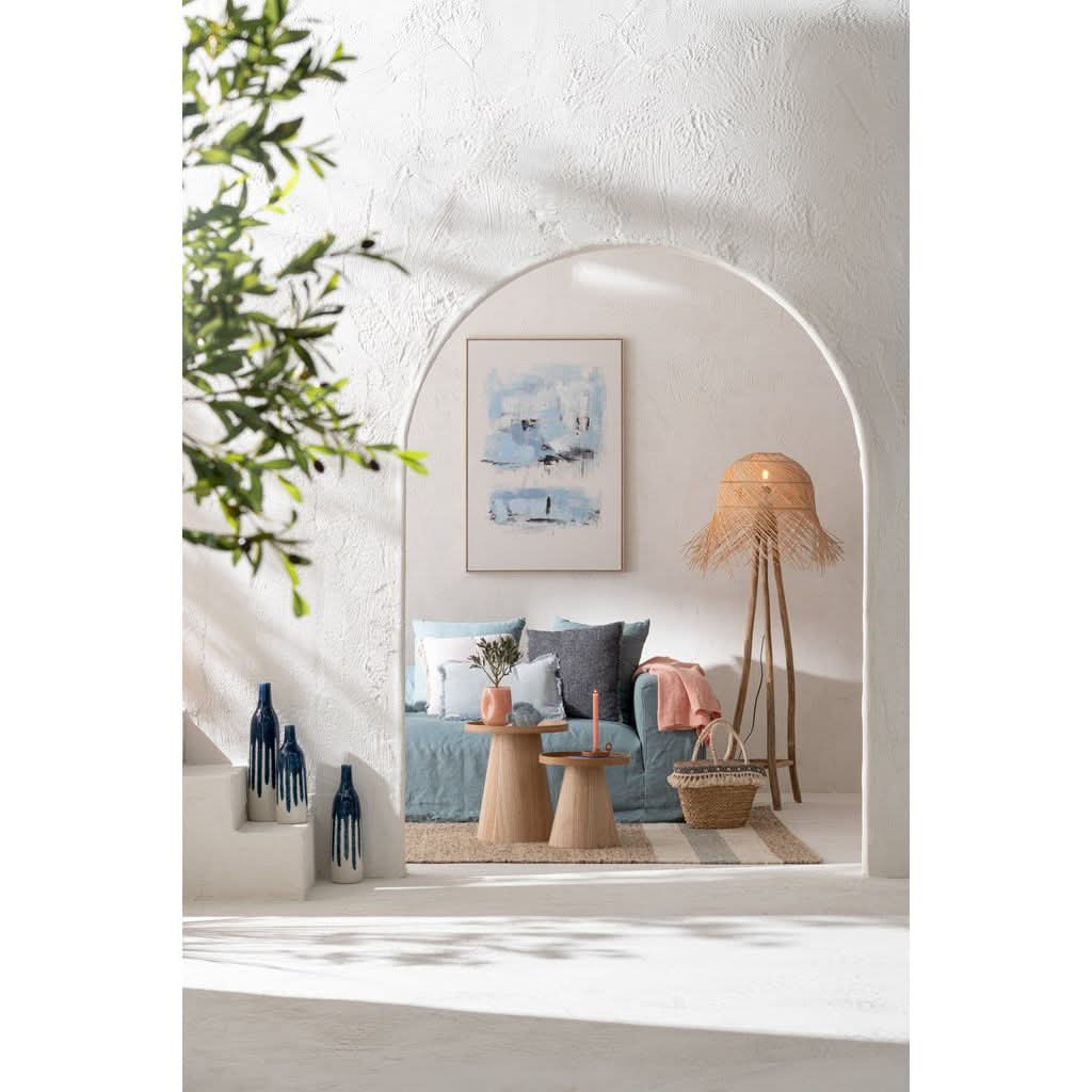 Mise en ambiance sous une arche blanche, canapé bleu et grand tableau abstrait