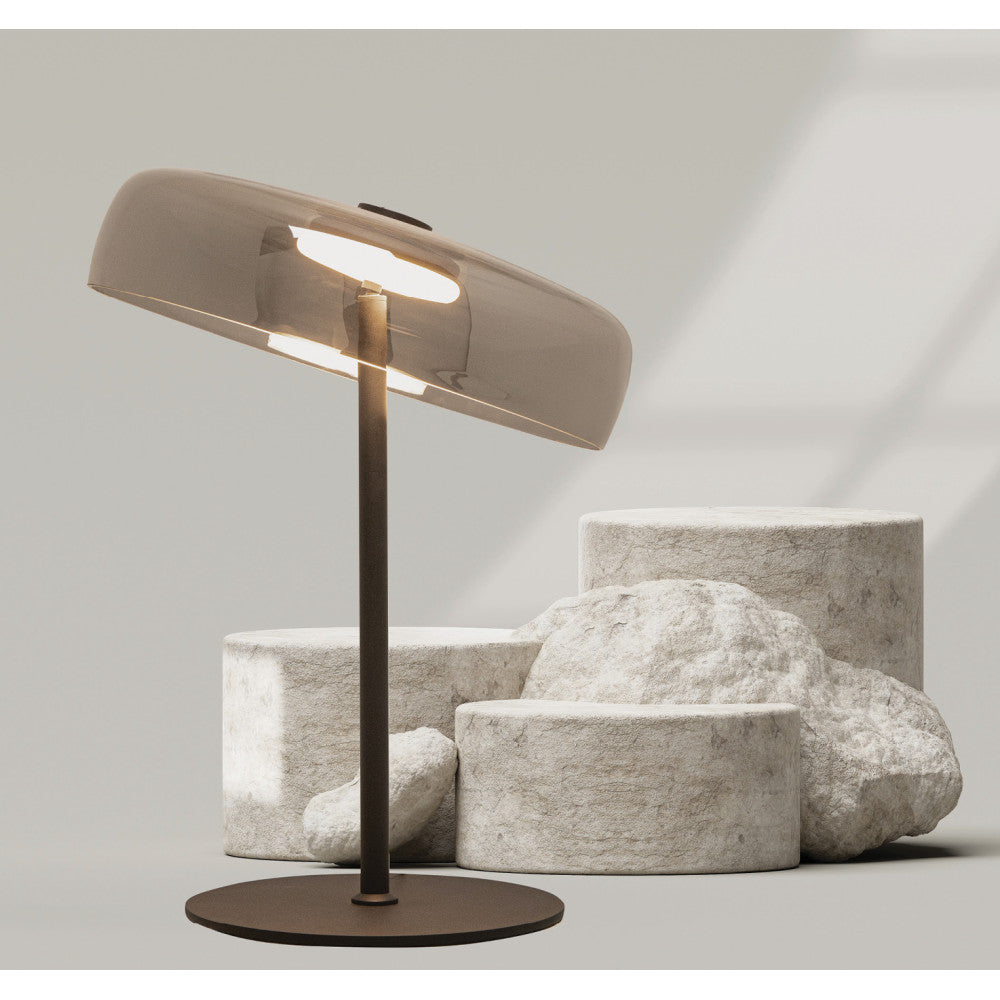 Vue rapprochée du luminaire allumé devant cylindres de pierre beige, détail de l'abat-jour