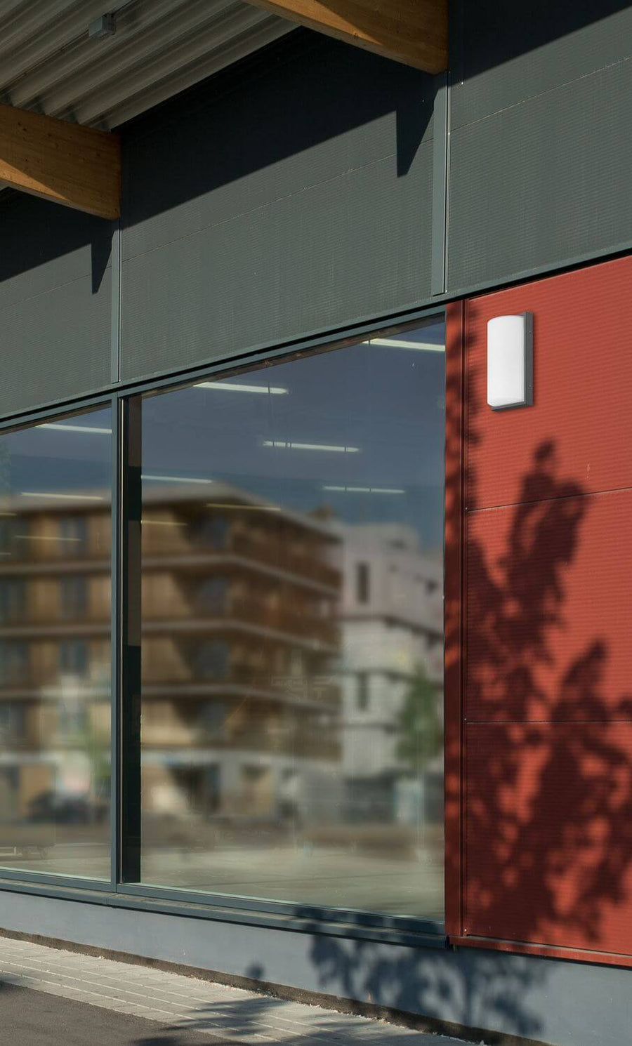 Vue rapprochée de l'applique anthracite sur panneau rouge, ombres de feuillage