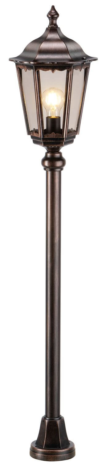Détail de la lanterne allumée, ampoule chaude et structure métallique noire et cuivrée.