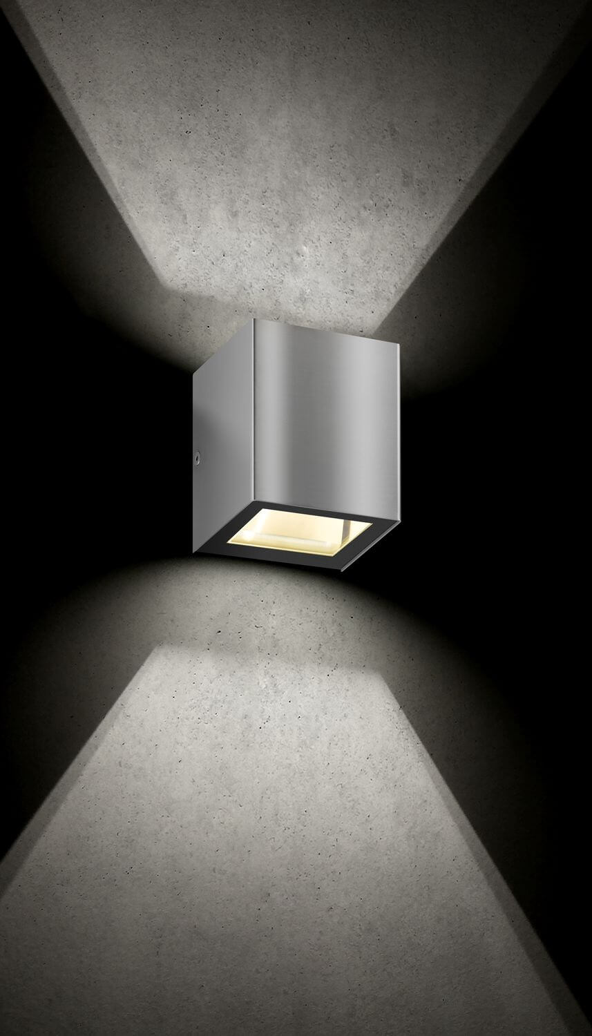 Vue rapprochée de l'applique inox et de son halo lumineux vers le bas