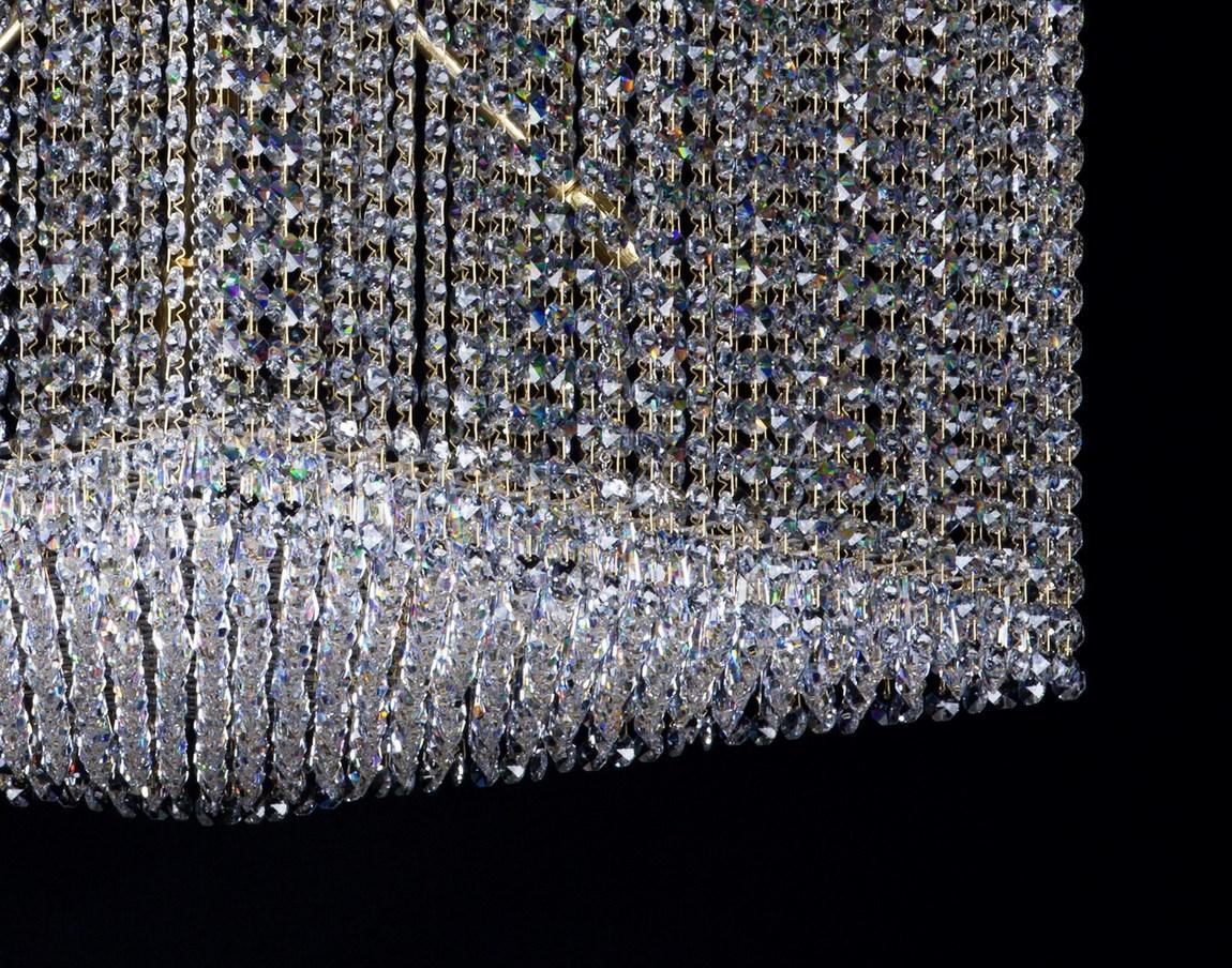 Détail rapproché des franges de cristal taillé et des maillons dorés du bas