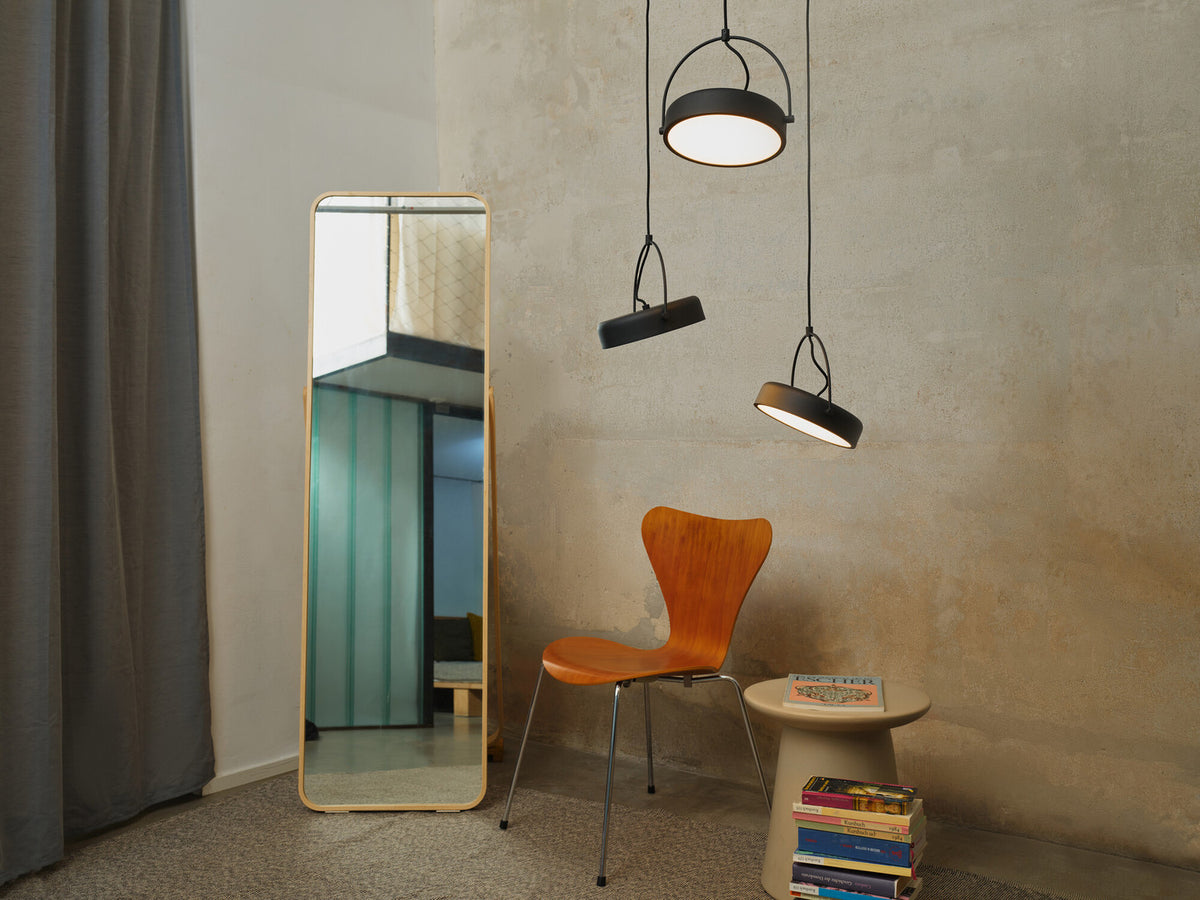 Mise en ambiance dans un salon avec miroir, chaise en bois et murs bruts.
