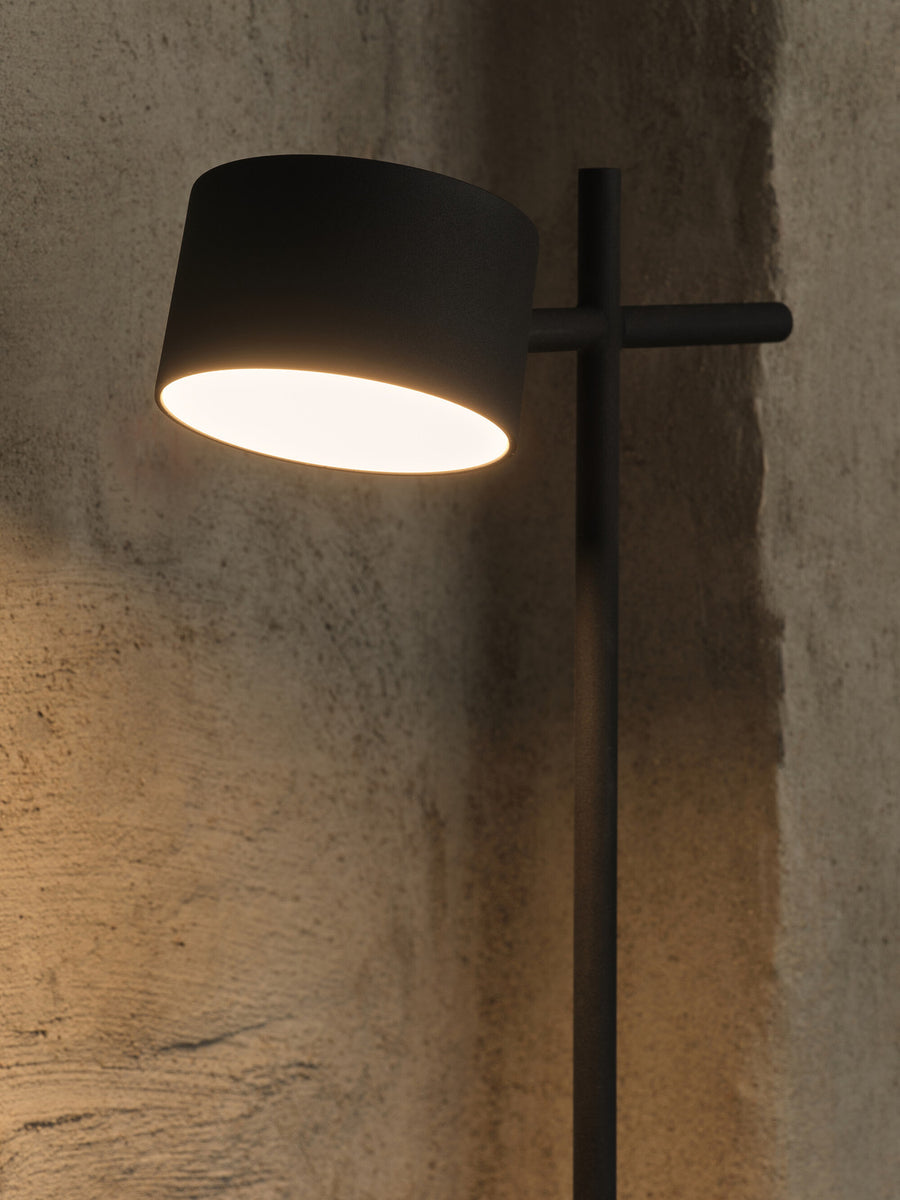 Détail de l'abat-jour allumé projetant une lumière chaude sur le mur