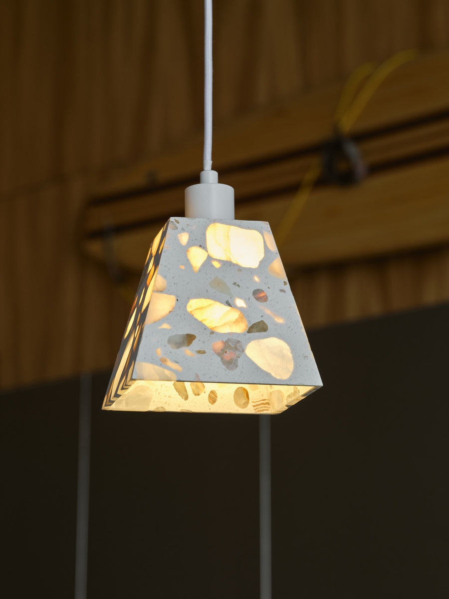 Détail de l'abat-jour allumé, motifs de terrazzo translucides et lumière chaude.