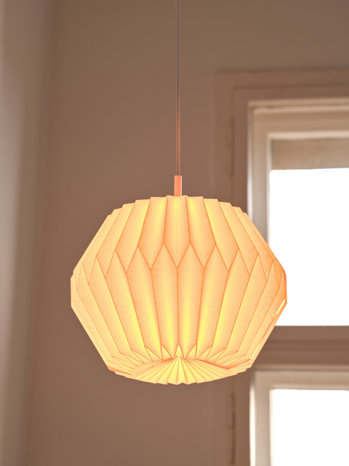 Détail de l'abat-jour allumé, lumière chaude près d'une fenêtre.