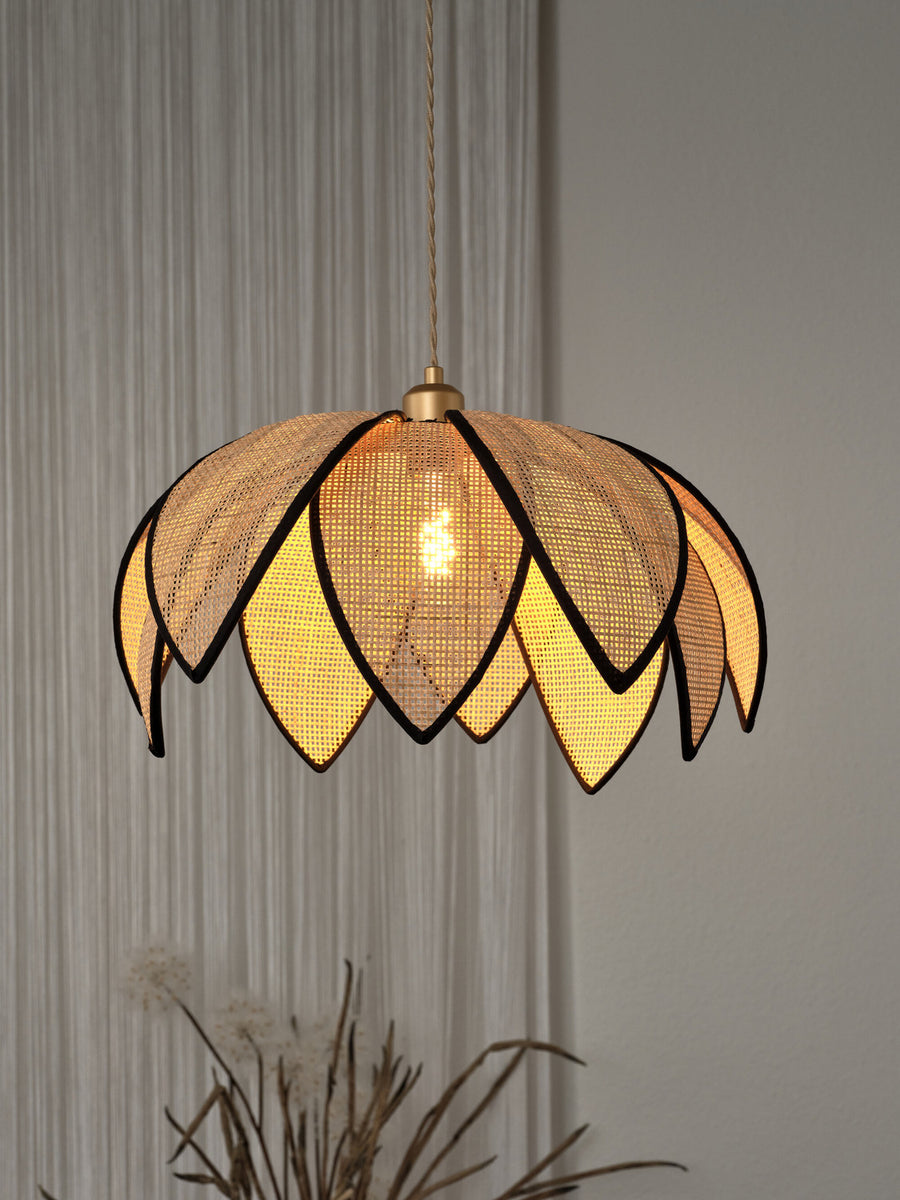 Détail de l’abat-jour lotus éclairé, lumière chaude à travers le cannage tressé.