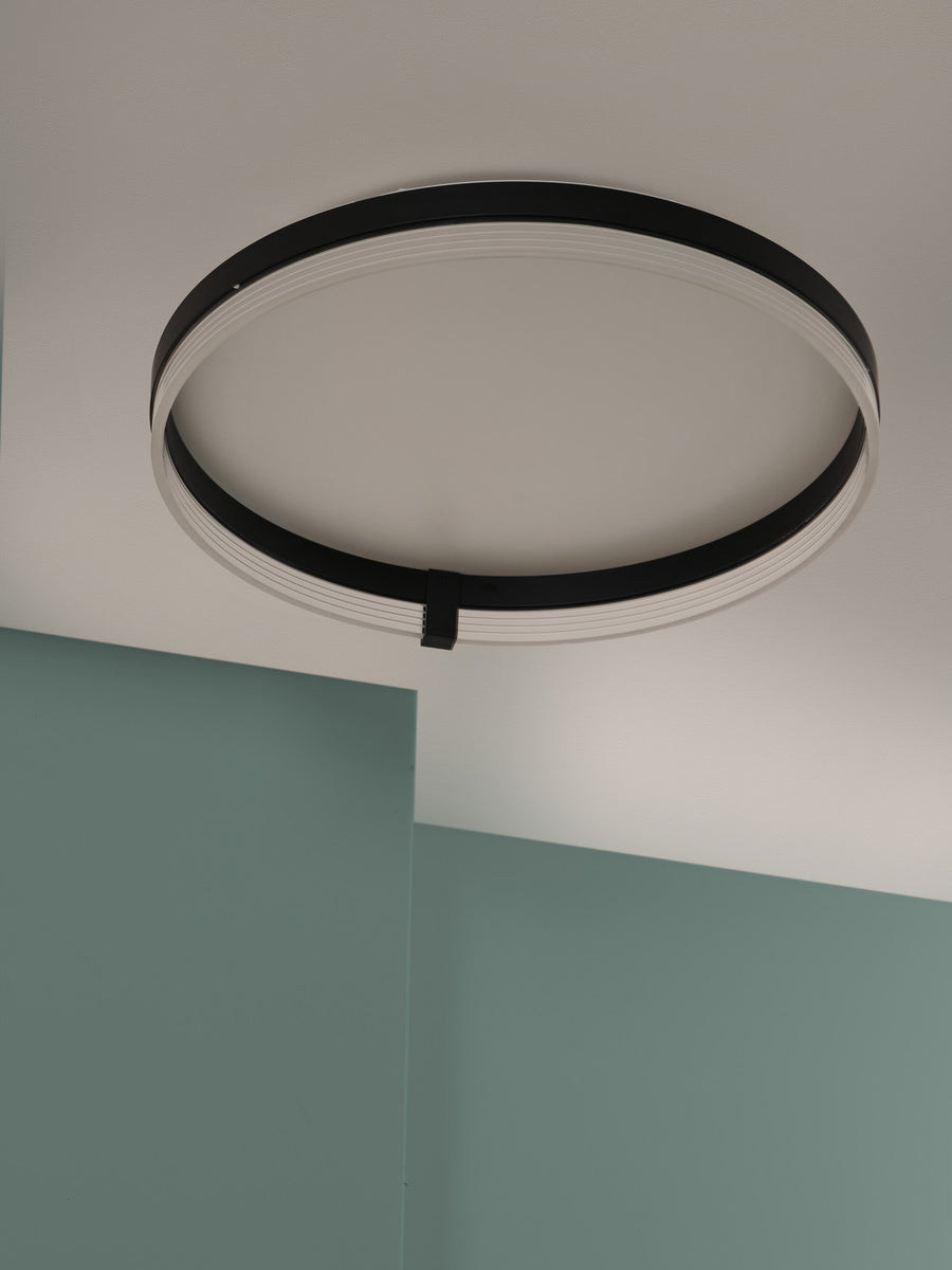 Détail du plafonnier noir vu sous un angle plongeant, plafond et mur vert.