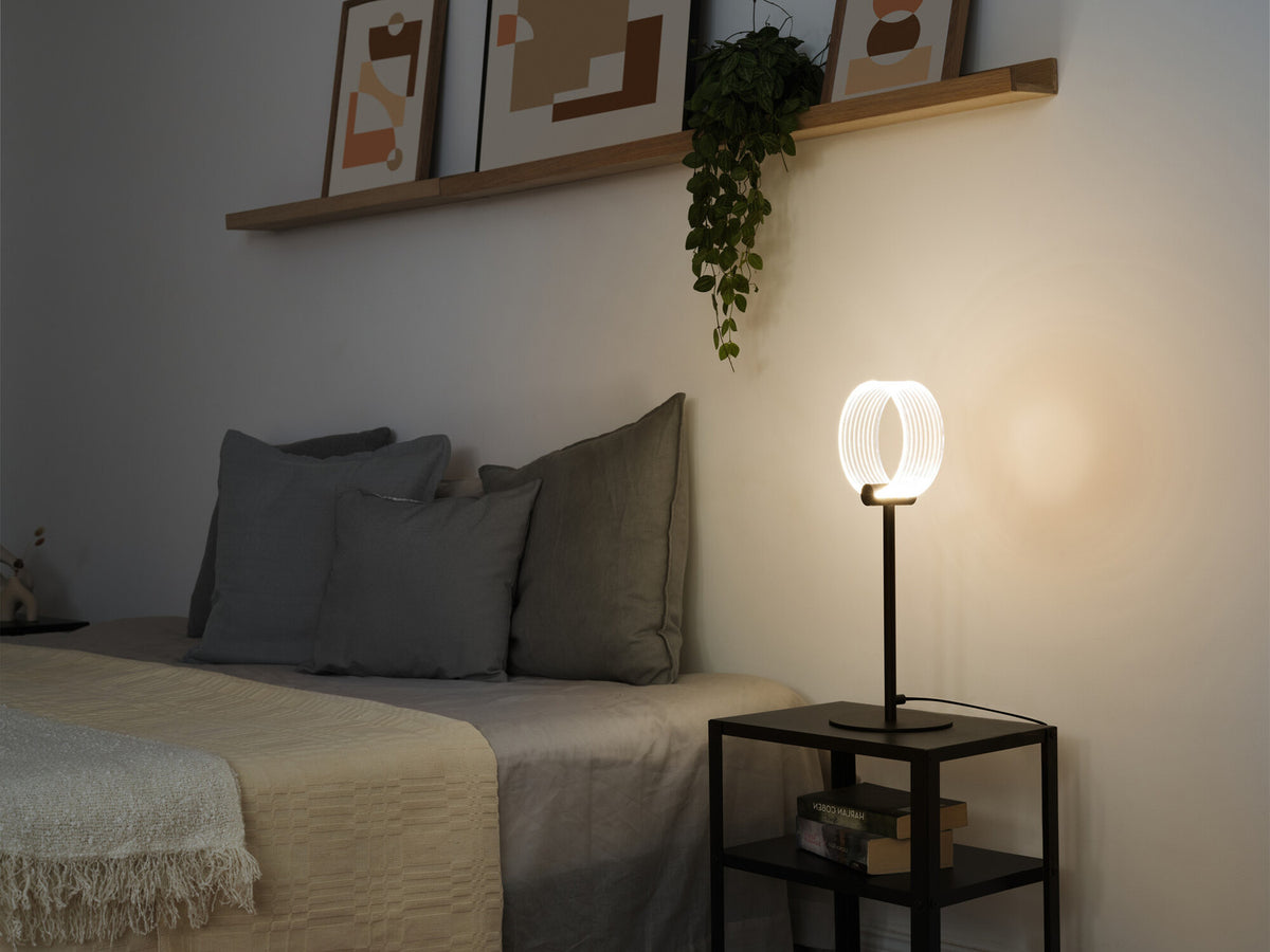 Lampe à poser diffusant une lumière chaude sur une table de chevet, scène de chambre.