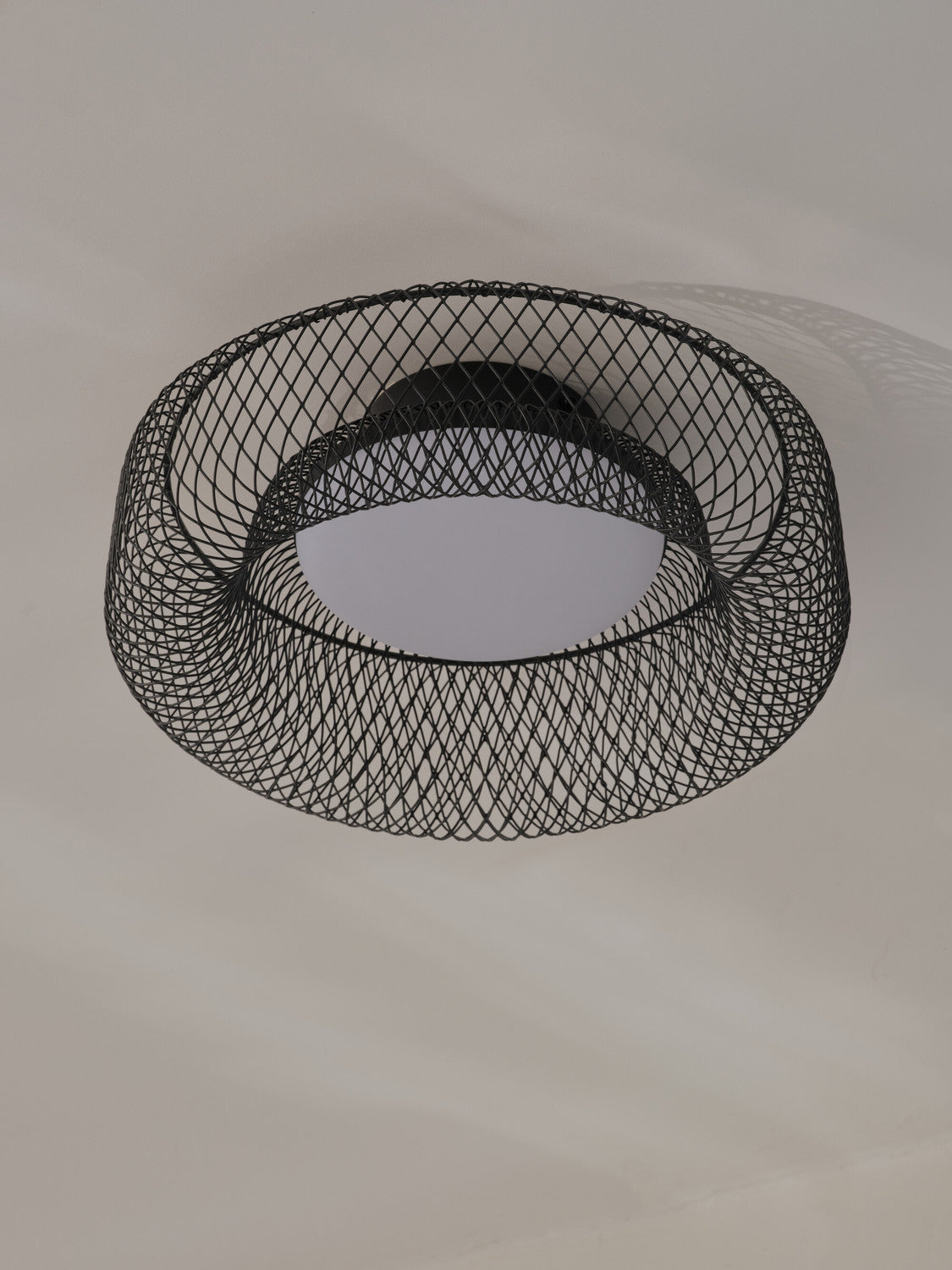 Vue rapprochée sous le plafonnier monté, détaillant la maille noire et le diffuseur.