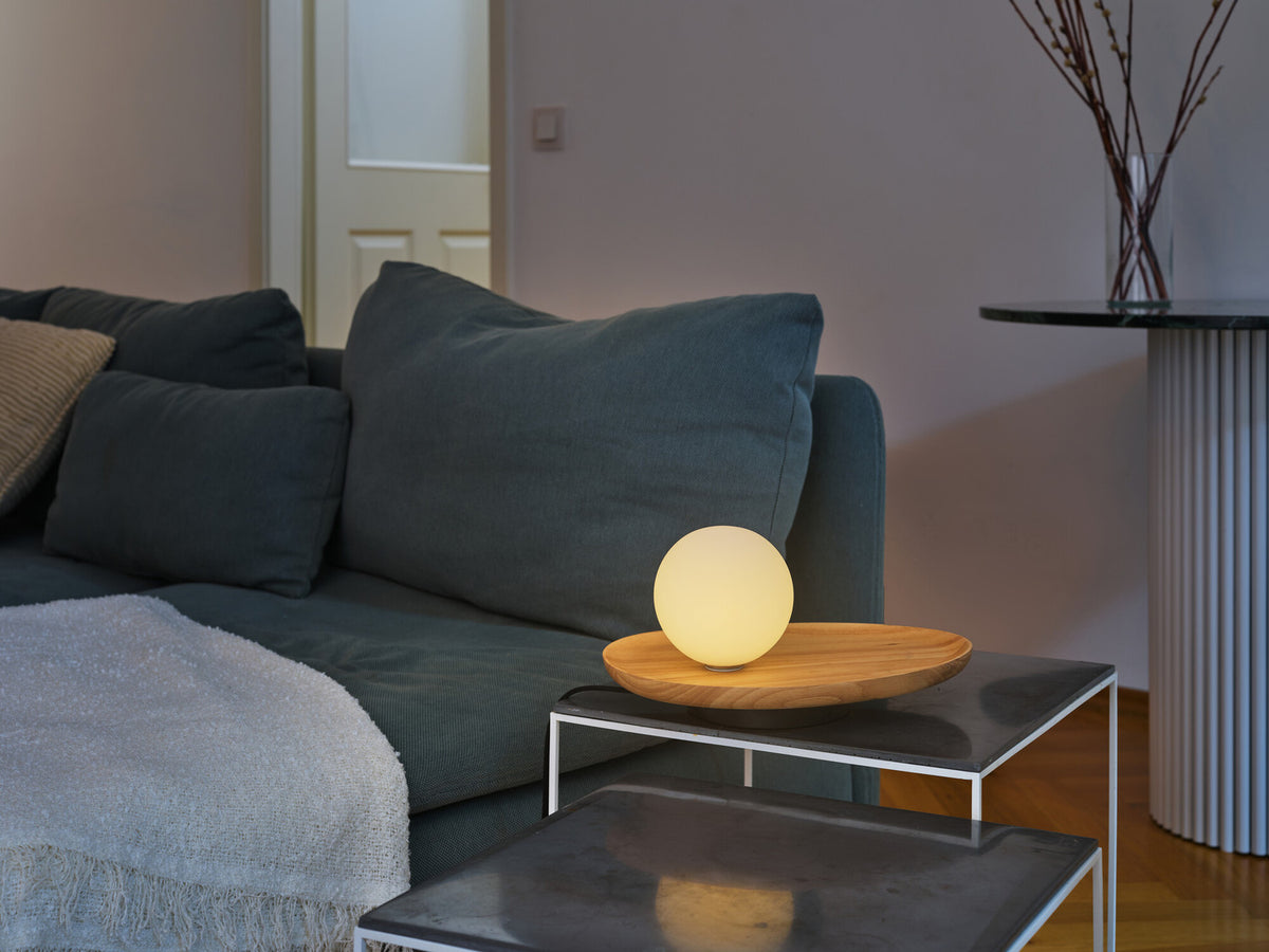 Mise en ambiance salon : lampe allumée sur table basse devant un canapé bleu nuit