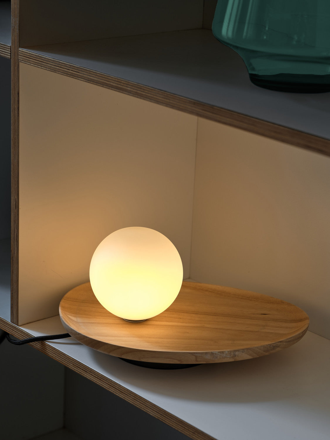 Lampe allumée dans une étagère en bois, halo chaud éclairant la niche