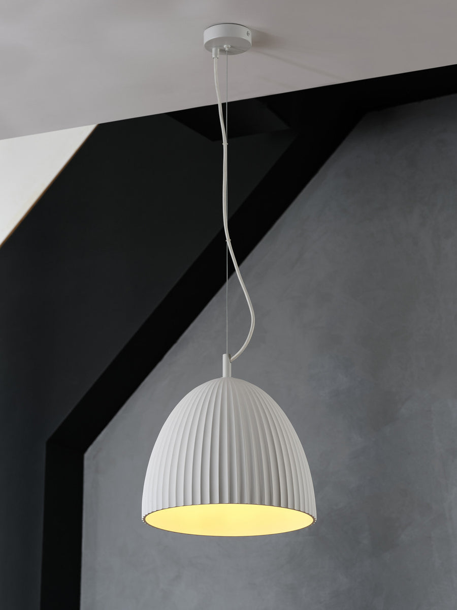 Vue en contre-plongée du luminaire allumé, abat-jour strié et plafond gris.