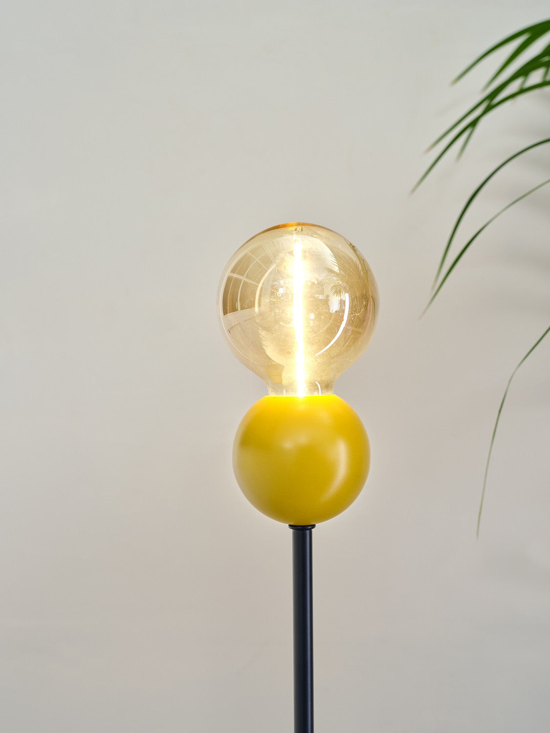 Détail rapproché de la sphère jaune et de l'ampoule transparente allumée